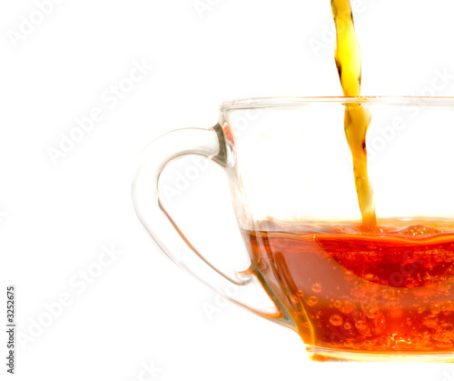 pouring  tea into a clear glass cafe style cup and saucer photo