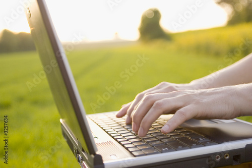typing on a laptop outside photo