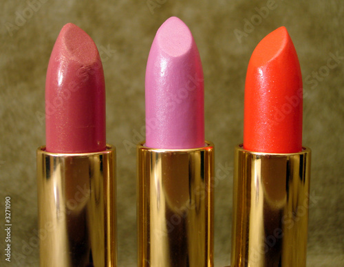 three colored lipsticks on background photo