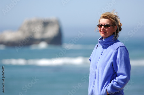 woman stands along rugged coastline