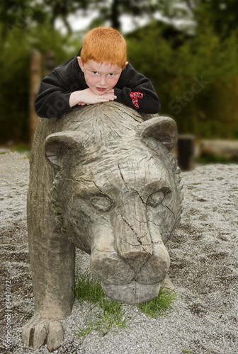 kid lying on a wooden lion
