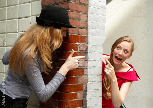 two girls peeking around the wall