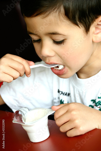 Young boy enjoying a tub of yogurt