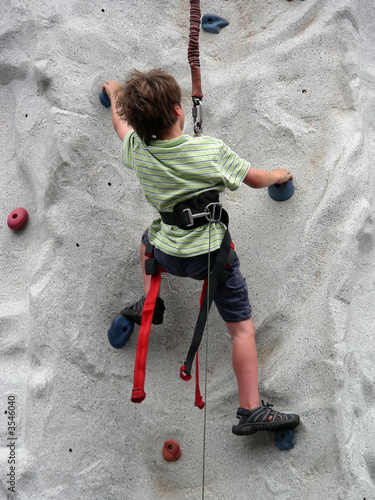 Young boy scaling a climbing wall post haste photo