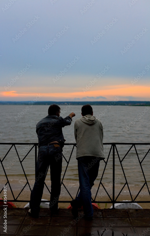 Fototapeta premium Two men on a river bay look at sunset #1