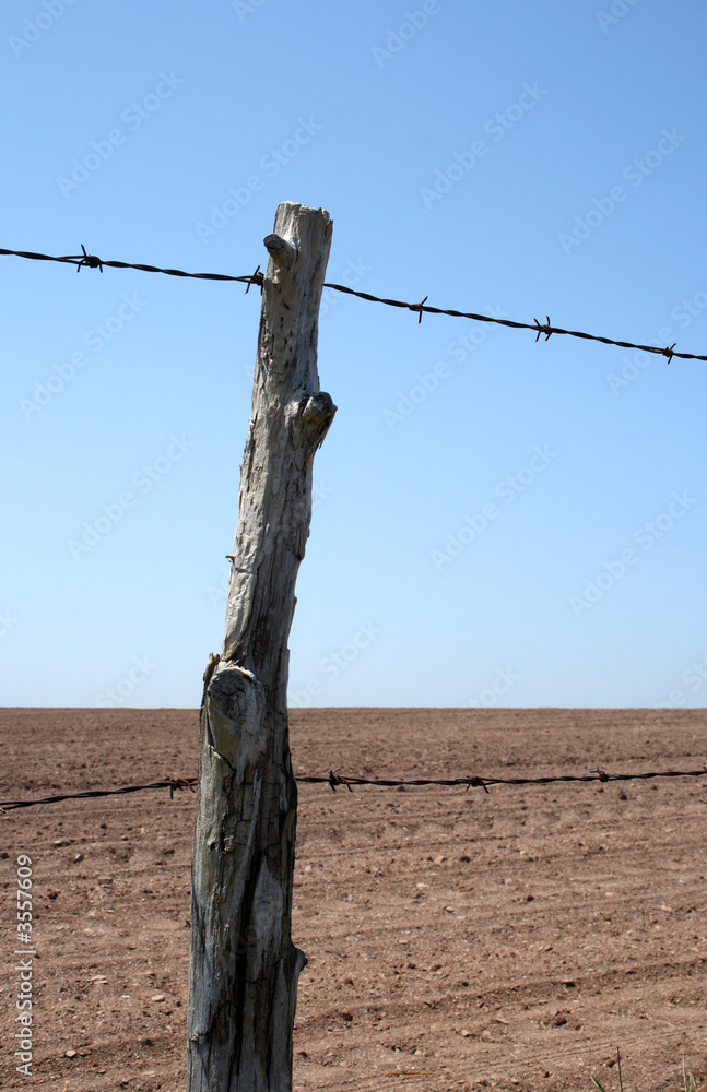 Old barbed wire farm fence and cultivated farmland in spring. Old barbed wire farm fence and cultivated farmland in spring.