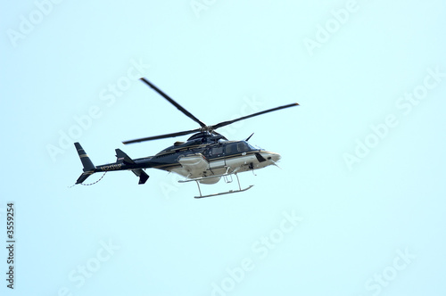 Fototapeta Naklejka Na Ścianę i Meble -  A Private Heliocopter flying against a Blue Sky