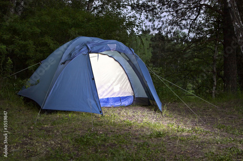 The camping tent in the evening forest