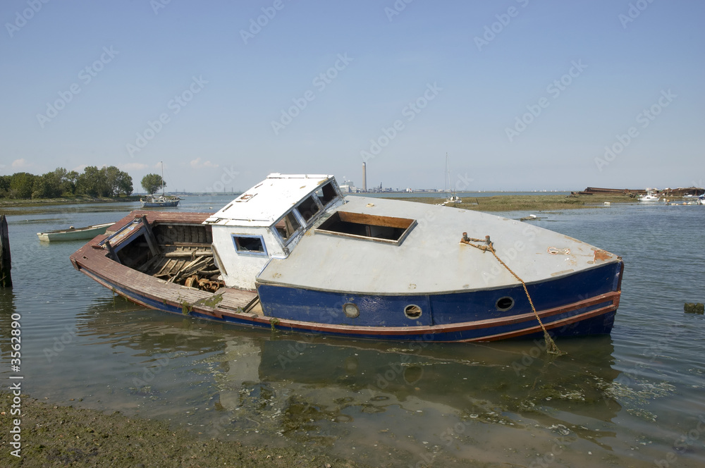An abandoned small boat on the edge o f the river Medway