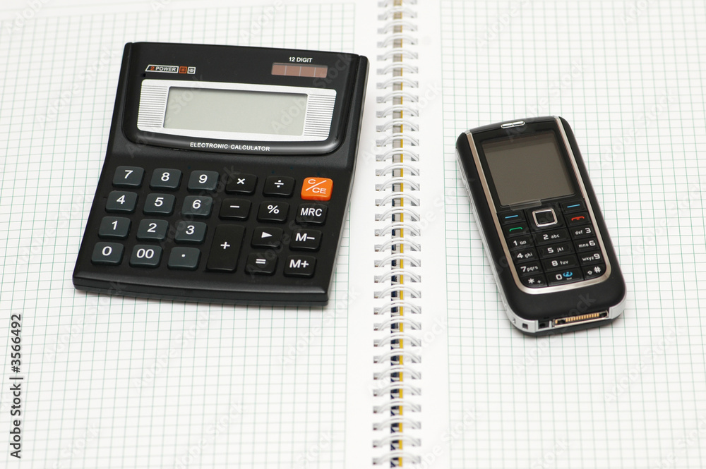 Mobile phone, calculator and pen on the notebook Mobile phone, calculator and pen on the notebook