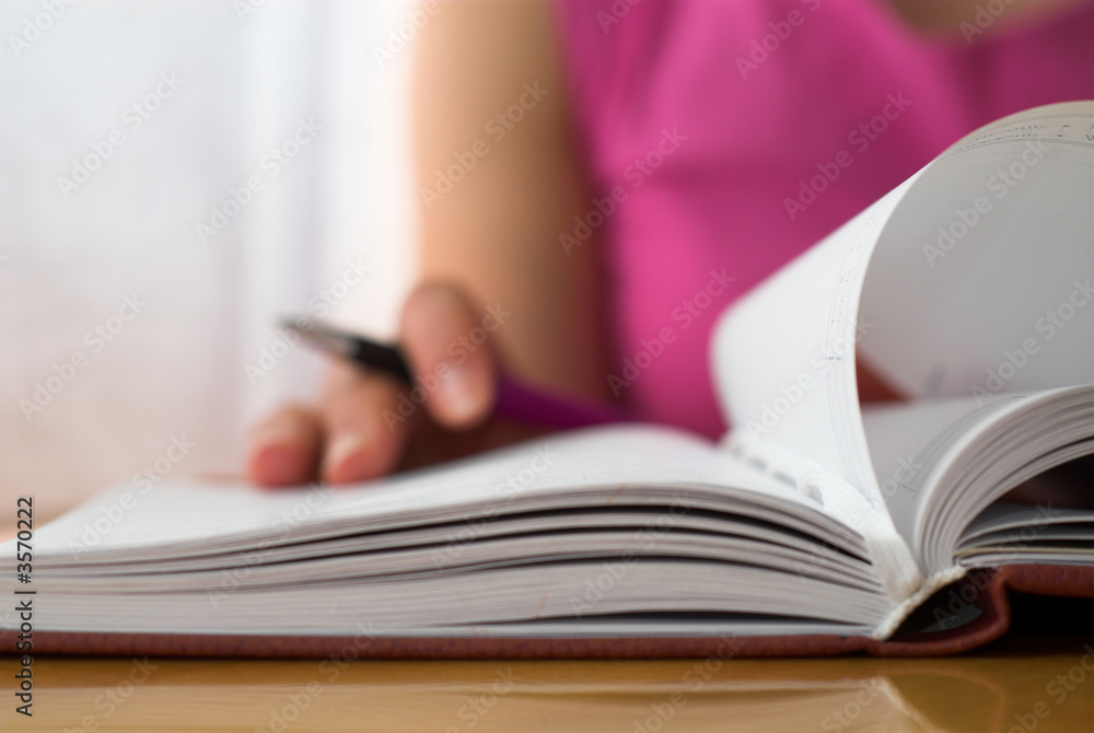 Young female is writing notes and planning her schedule. Young female is writing notes and planning her schedule.