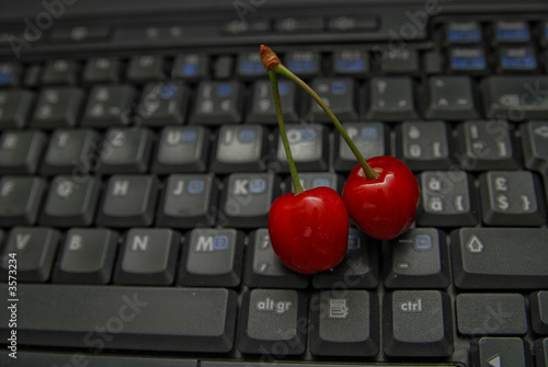 fresh cherry on laptop keyboard photo