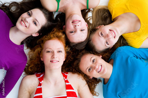 fünf wunderschöne Mädchen liegen am Boden und lächeln 