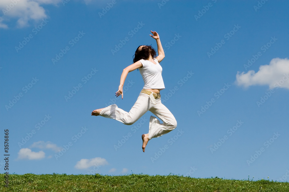 happy young woman is jumping in green grass happy young woman is jumping in green grass