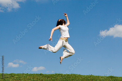 happy young woman is jumping in green grass