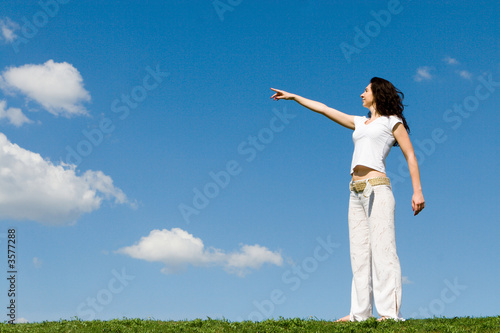 young woman on a green meadow and show something