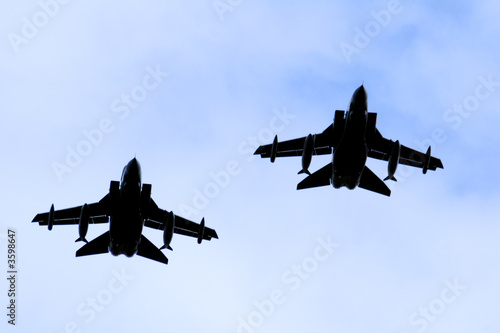 A silhouette of two Royal Air force RAF Panavia Tornado jet fighters against a blue sky. photo