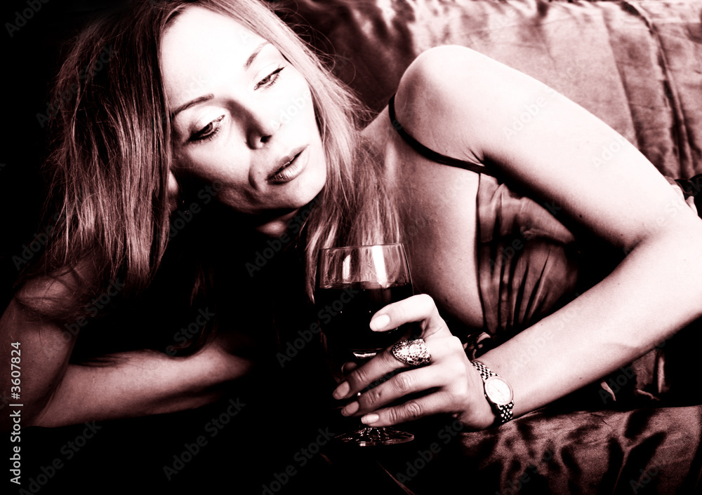 Young woman lying on sofa with a glass of wine Young woman lying on sofa with a glass of wine