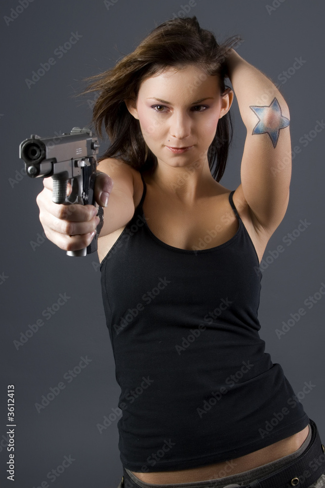 Brunette with star tatoo pointing handgun towards camera Brunette with star tatoo pointing handgun towards camera