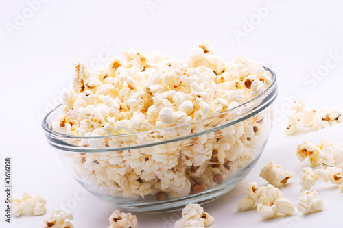 Closeup of glass bowl of popcorn with few peaces throw around