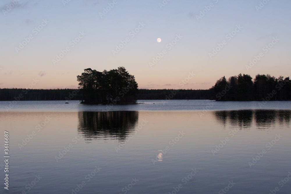 Mond im Sonnenuntergang über dem Wasser