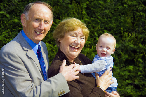Smiling grandparents holding happy baby boy portrait
