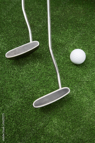 Two clubs and ball for a golf on a grass