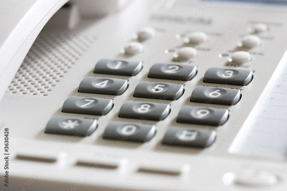 White office desk phone close-up. Focus on the center button White office desk phone close-up. Focus on the center button