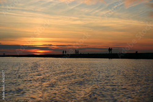 Silhouettes of people on a pier on a background of a sunset