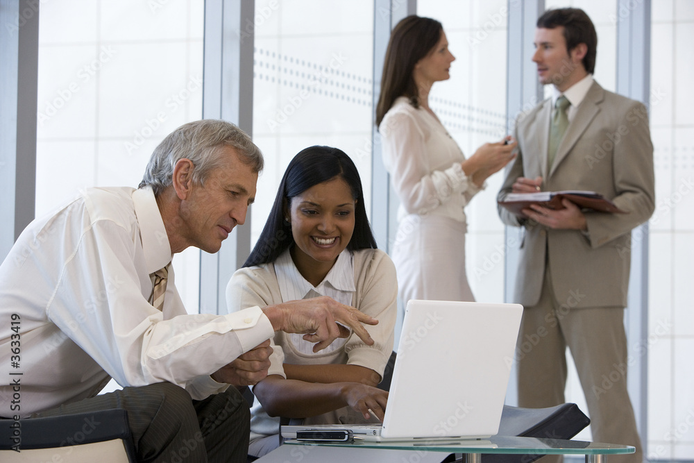 Successful business team of four with two on laptop Successful business team of four with two on laptop