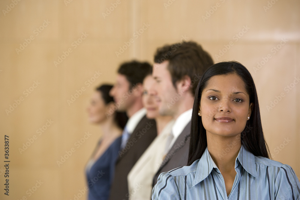 Confident young business woman with team behind