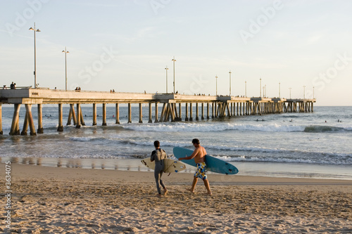 Two surfers walking along the beach