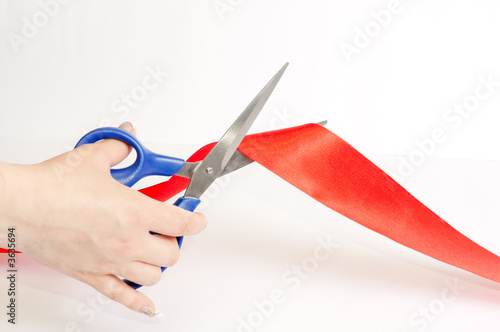 Scissors cutting a red tape