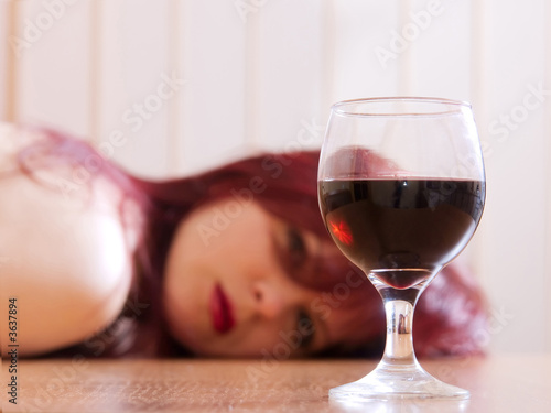 The girl laying on a table and a glass with wine