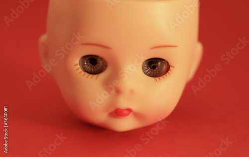 A close up of a doll's head on a red background