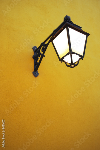 Bright light from an old street lamp in a yellow wall.