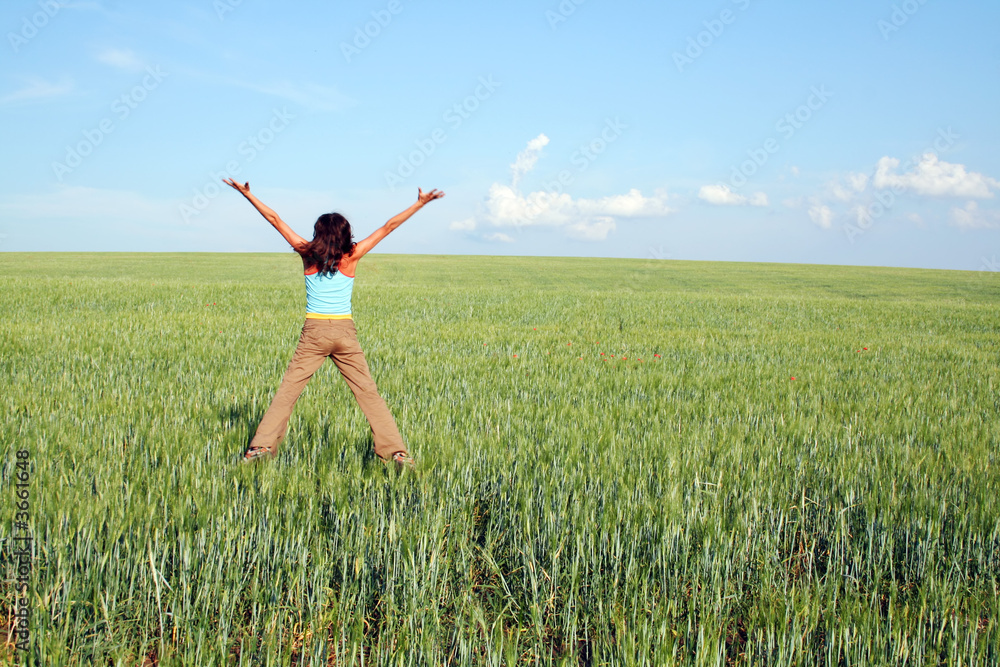 Jumping girl on green grass on a background of the sky Jumping girl on green grass on a background of the sky