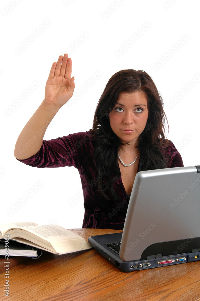 A young woman at her desk raising her hand with a question A young woman at her desk raising her hand with a question