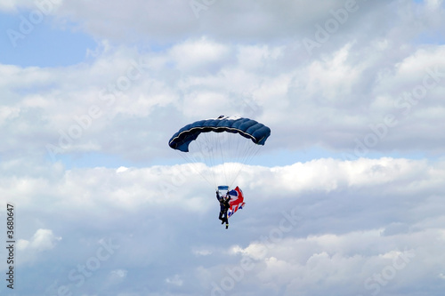 Parachutist with a Union Jack flag against a blue cloudy sky.