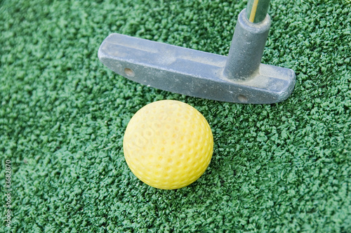 A closeup of a putter and golf ball from a crazy golf course.