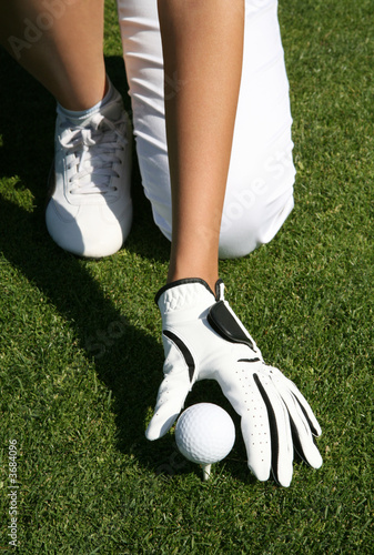 A woman golfer placing the golf ball on the tee