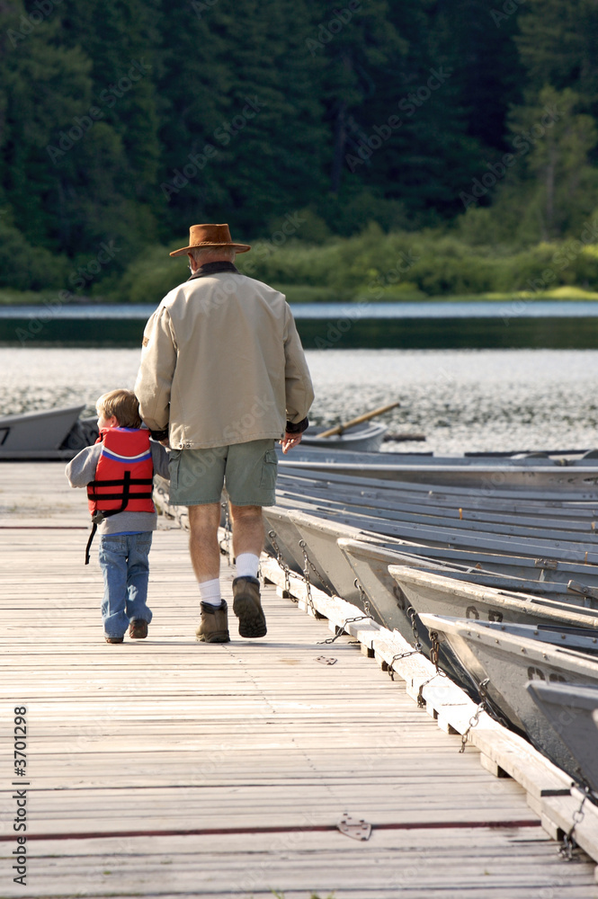 Grandpa and grandson walking on a dock
