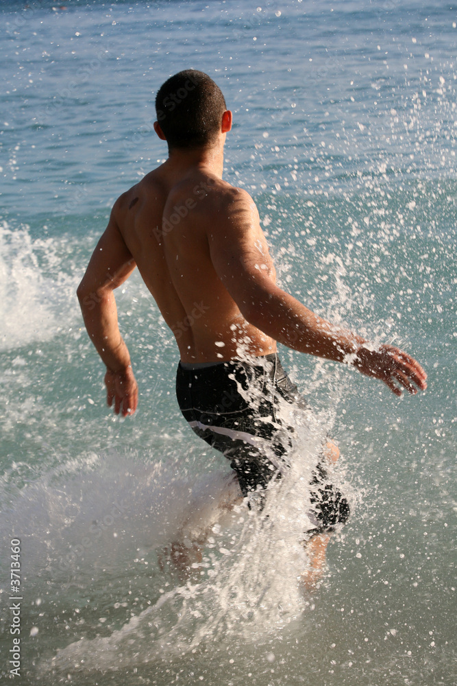 Fototapeta premium Young man running in the water