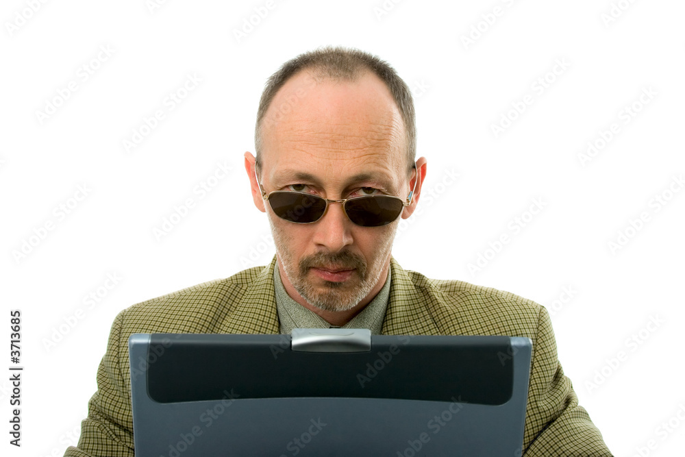 Serious  businessman with laptop looking over glasses