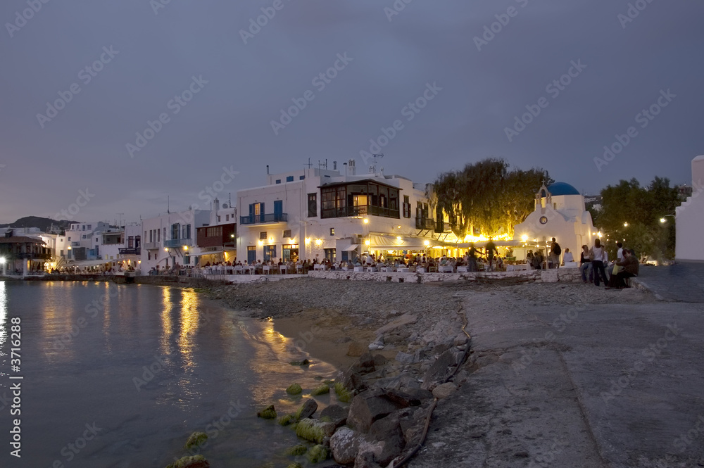 People at restaurants on Mykonos beach at dusk, Greece