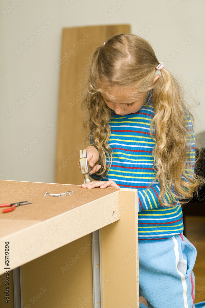 Girl helping to assemble a new furniture Girl helping to assemble a new furniture