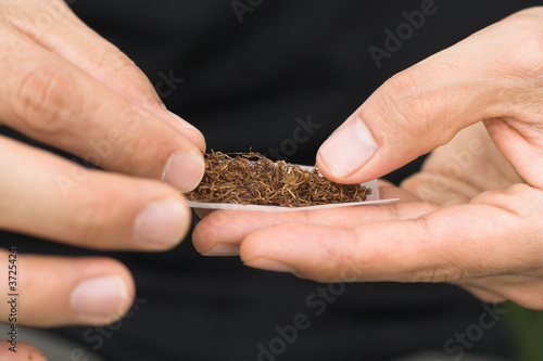 photo showing hands of a male rolling tobbacco