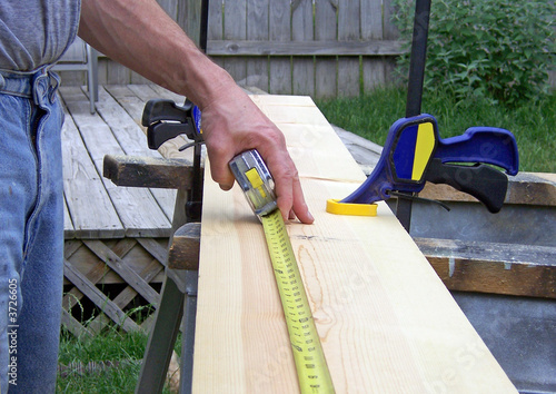 man measuring lumber
