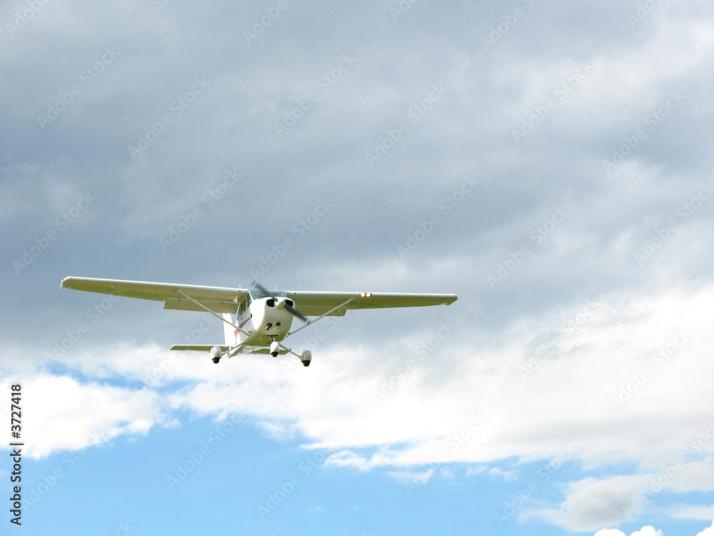 weisses Sportflugzeug fliegt durch blauen und wolkigen Himmel weisses Sportflugzeug fliegt durch blauen und wolkigen Himmel