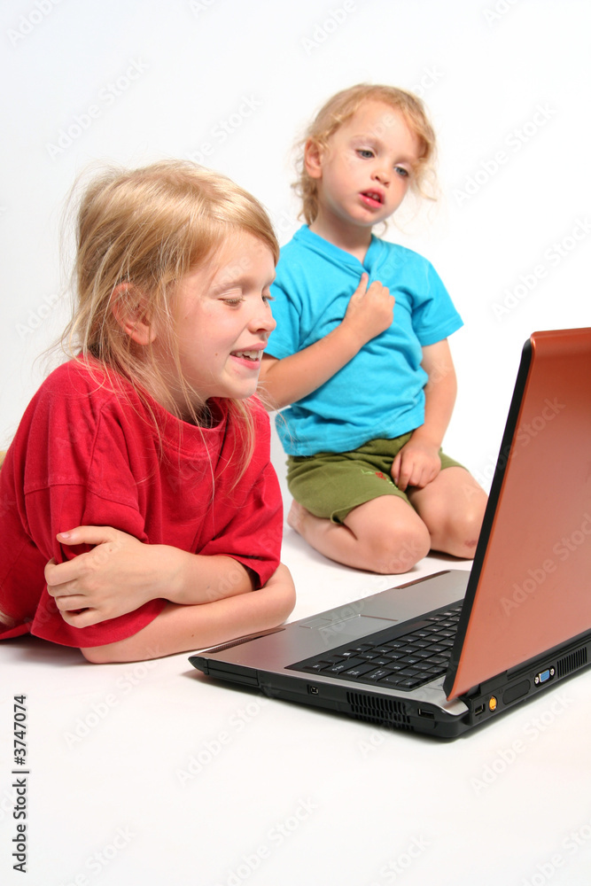 Two little girls playing on laptop on a white background